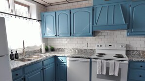 A kitchen with blue cabinets, white appliances, and a granite countertop. - Cozy 3-Bedroom Home, Great Location in Downtown Huntingdon (Huntingdon)