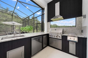 Una cocina moderna con un ventanal grande, una parrilla empotrada y vistas al exterior.
