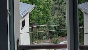 A view through a window of a building with a mountain backdrop, a tree, and a fence. - L'Ostu Di San Giacu (Boves)