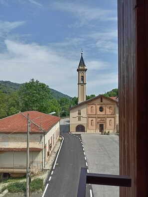 Una calle que conduce a una iglesia con un campanario, rodeada de edificios y vegetación.