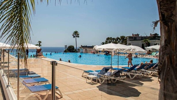 A poolside area with lounge chairs and umbrellas, overlooking a swimming pool and the sea. - Luxury apartment, swimming pool, tennis, beach (Cannes)