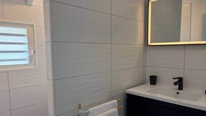 A bathroom with white tiles, a window, a mirror, a sink, and a towel rack. - Villa Koray, Orient Bay, pool , central location (Marigot)