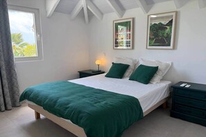 A bedroom with a bed, two nightstands, a lamp, and two framed pictures on the wall.