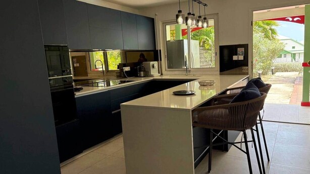 Una cocina moderna con una isla central, muebles oscuros y vistas al exterior.