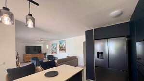 A modern kitchen with a built-in refrigerator, a dining area with a table and chairs, and a living room with a sofa and a TV. - Villa Koray, Orient Bay, pool , central location (Marigot)