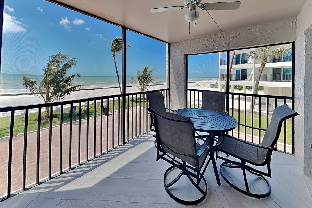 Un balcone con tavolo e sedie, vista su una spiaggia e l'oceano.