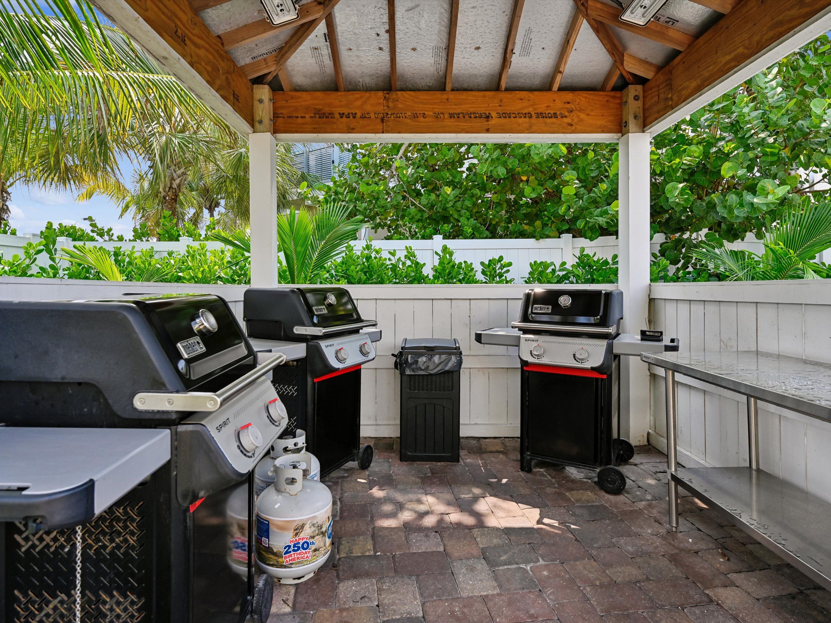 Une terrasse extérieure équipée de deux barbecues, d’une poubelle et d’une bouteille de propane.