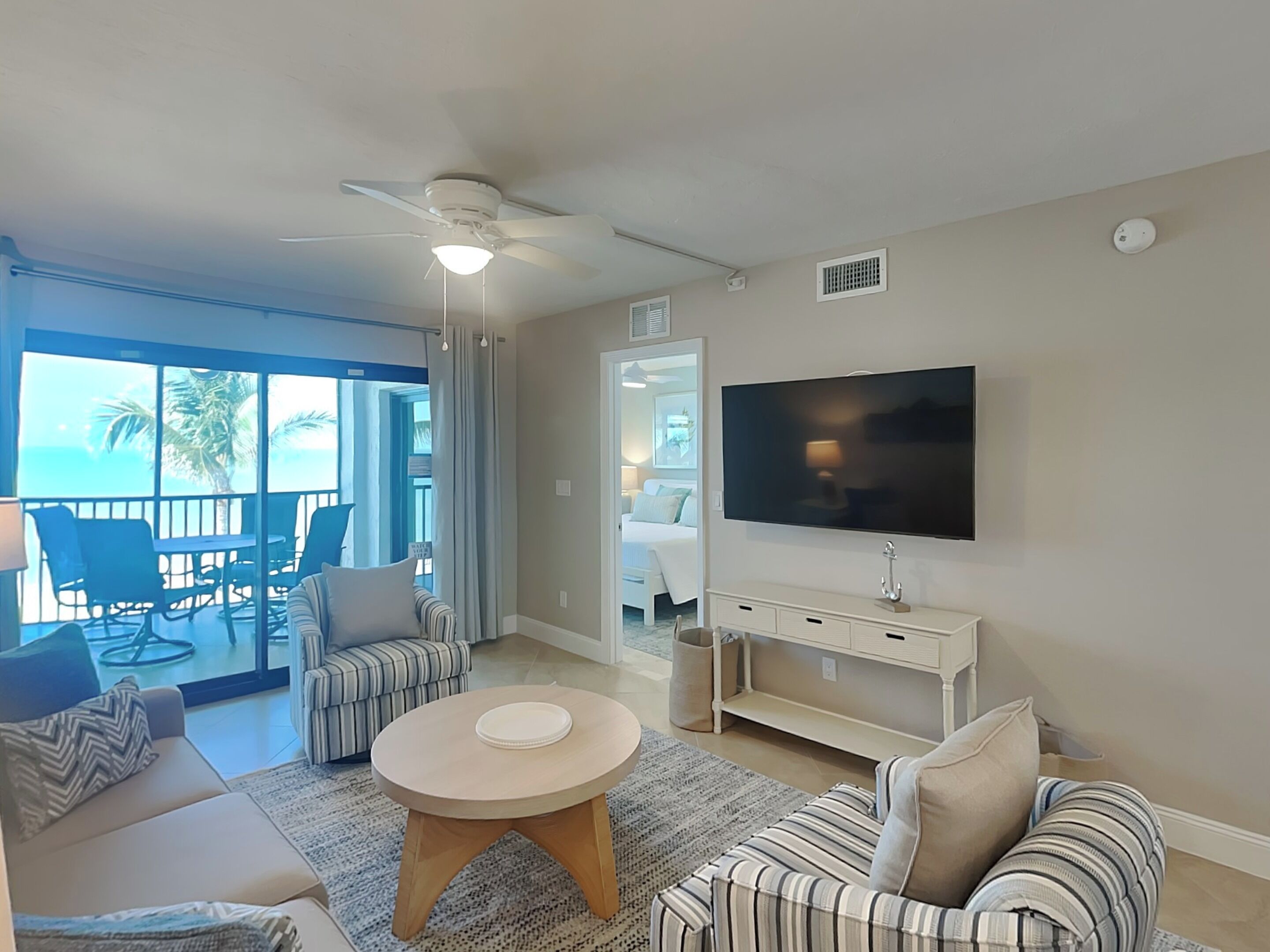 A living room with a TV, sofas, a coffee table, and a balcony with chairs.