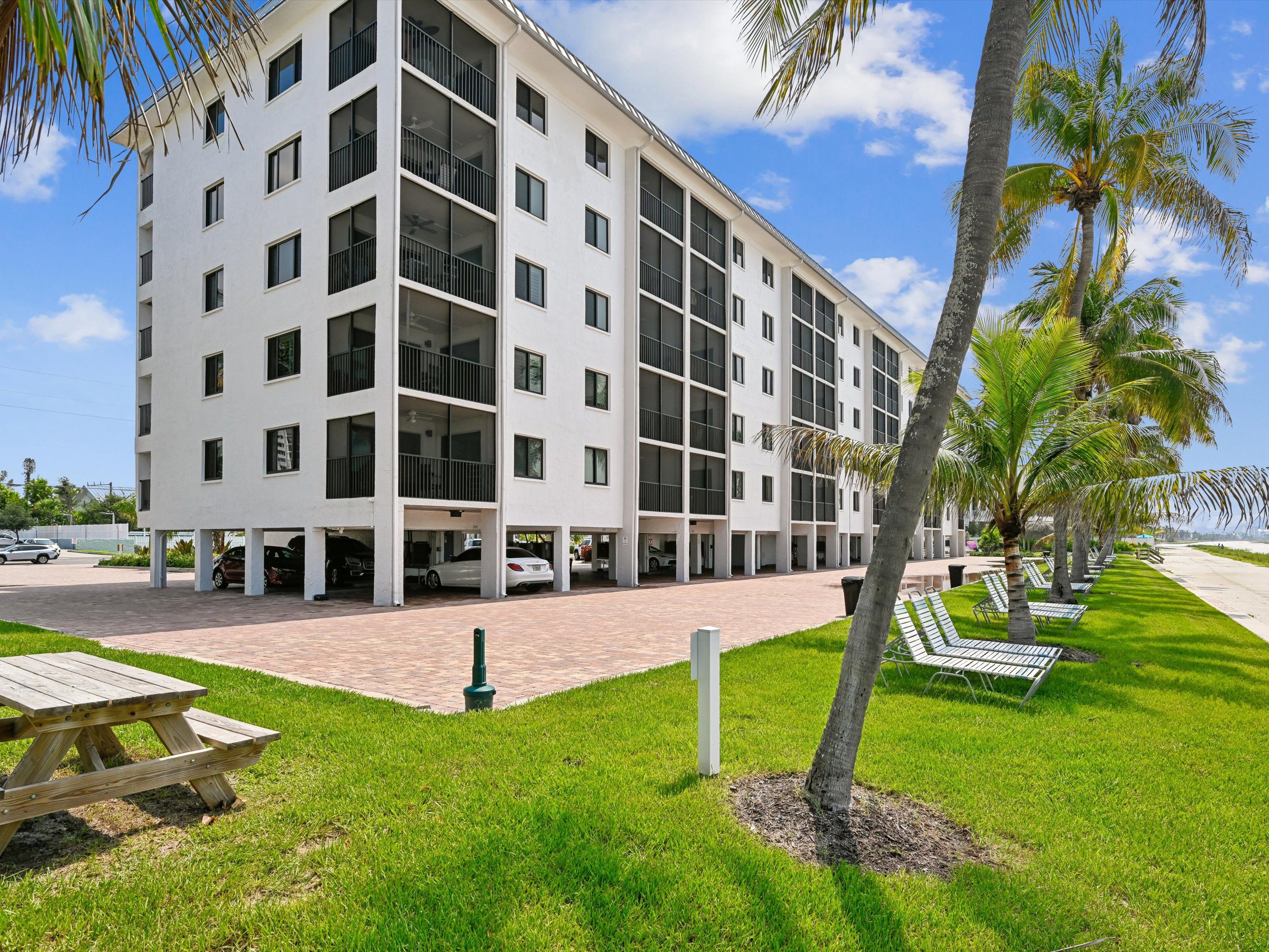 A multi-story hotel with a flat facade, outdoor seating, and palm trees.