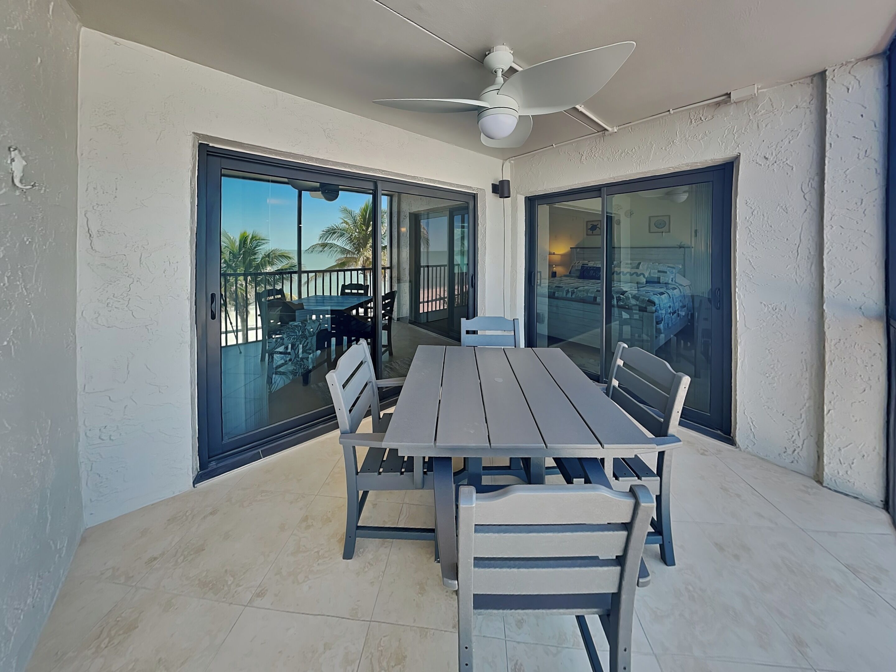 A dining area with a table and chairs, large sliding glass doors, and a ceiling fan.