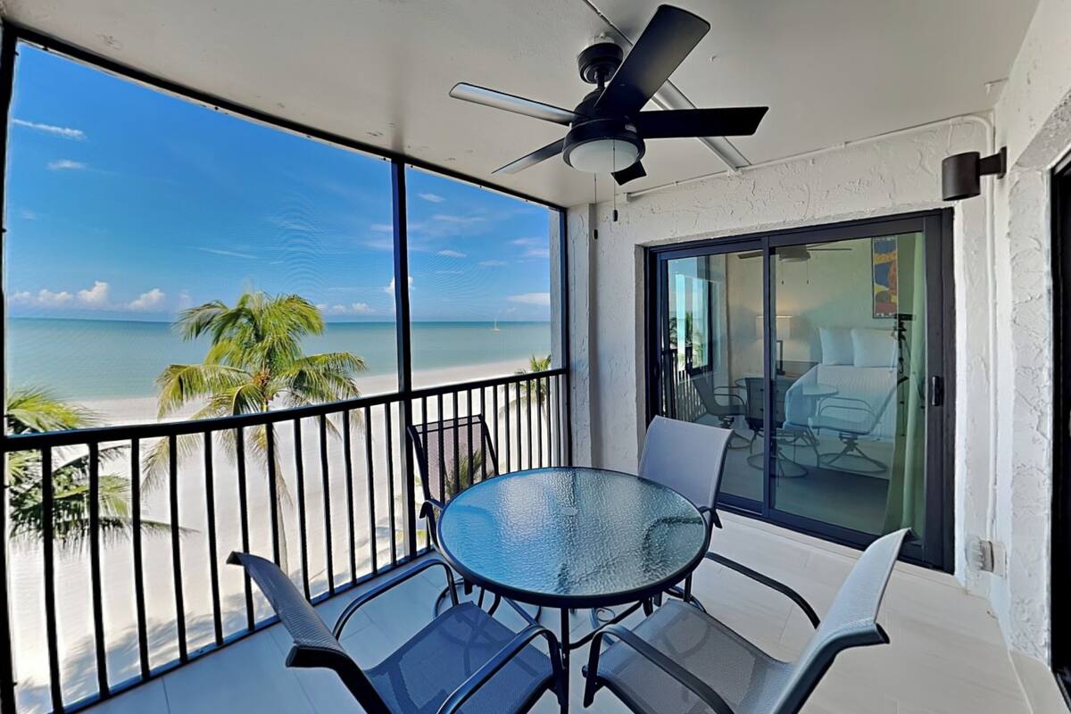 A balcony with a glass door, a ceiling fan, and a table with chairs.