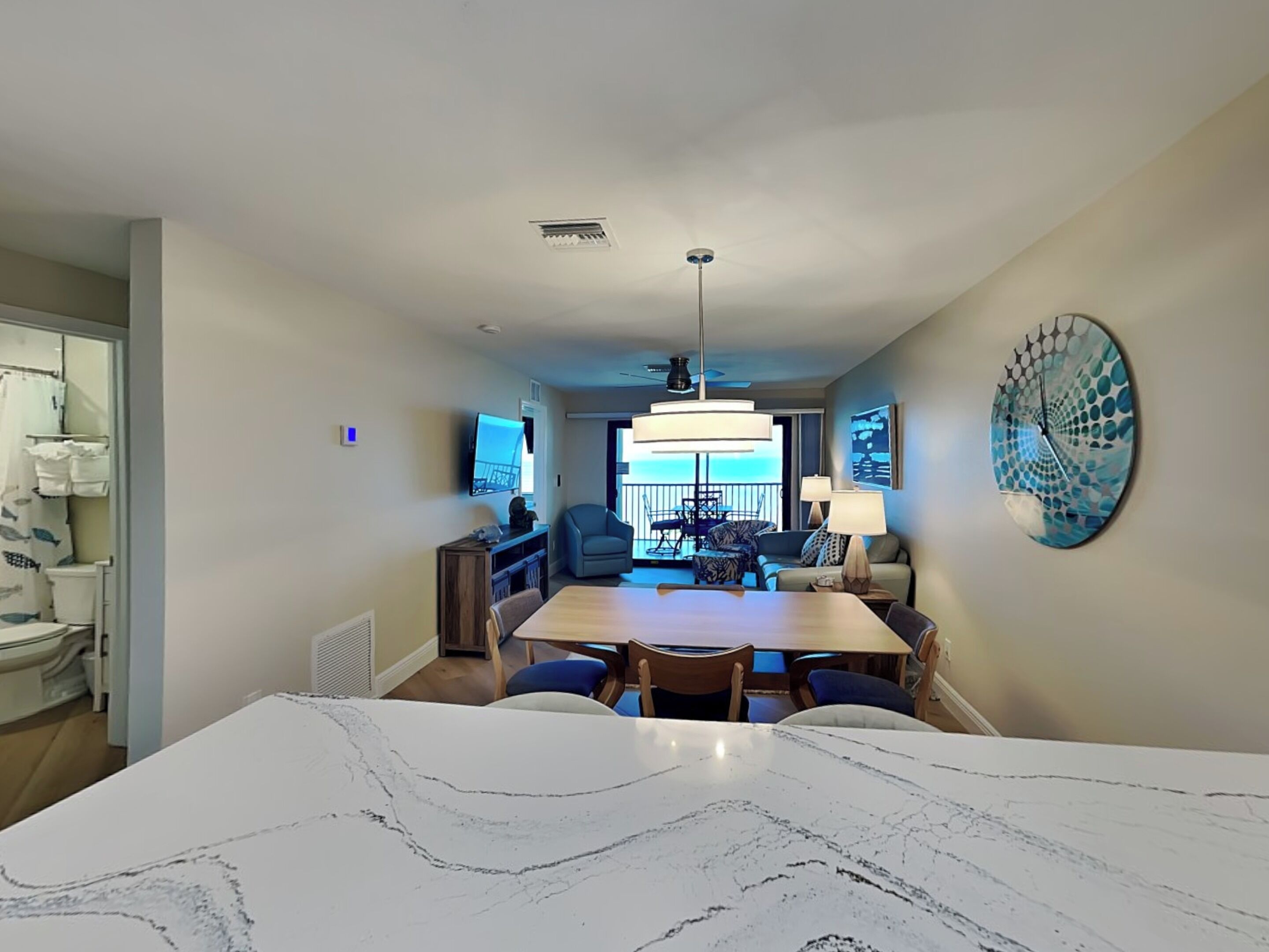Ein modernes Wohnzimmer mit einem Marmoresszimmer, einem Deckenventilator und einer großen Uhr an der Wand.