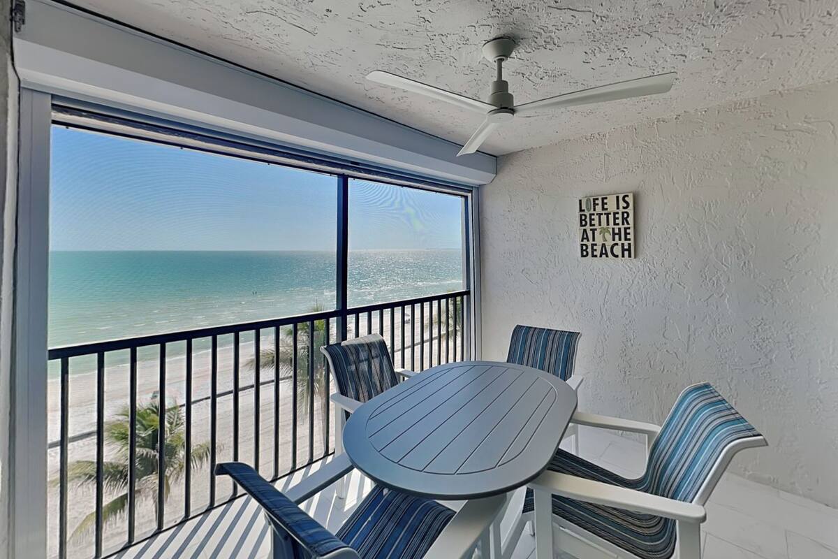 Un balcon avec vue sur l’océan, un ventilateur de plafond et une pancarte sur laquelle on peut lire : « La vie est plus belle à la plage. »
