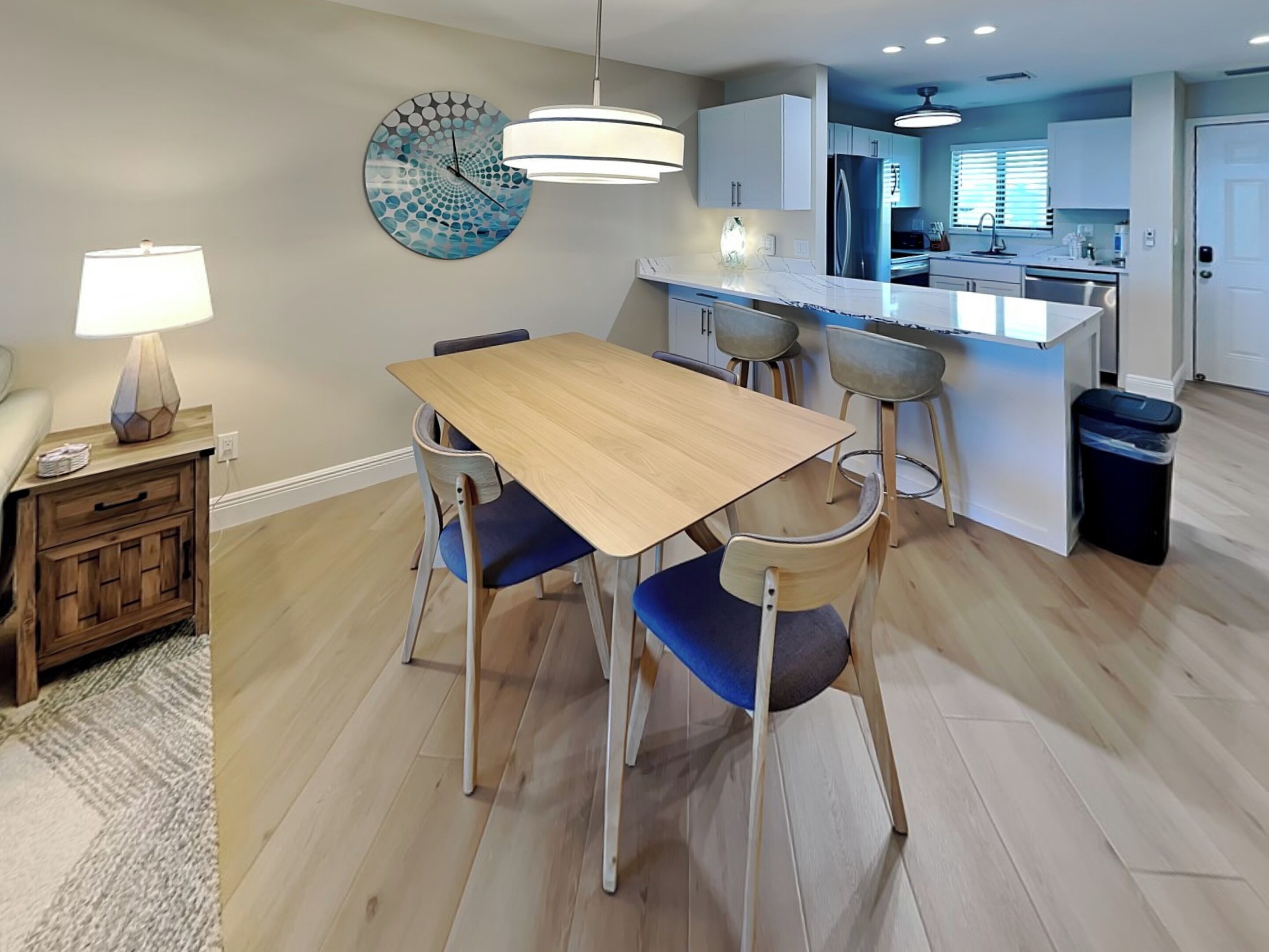 Een moderne keuken met witte kastjes, een roestvrijstalen koelkast en een inbouw eiland met barstoelen.