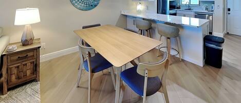 Een moderne keuken met witte kastjes, een roestvrijstalen koelkast en een inbouw eiland met barstoelen.