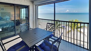 A balcony with a table and chairs, a ceiling fan, and a view of the ocean. - Seaside 5 by Distinctive Beach Rentals (Fort Myers Beach)