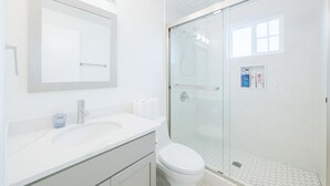 Un bagno moderno con cabina doccia in vetro, un lavandino bianco e un water.