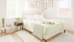 Un dormitorio con cama, mesitas de noche, una planta en maceta e impresiones botánicas enmarcadas en la pared.