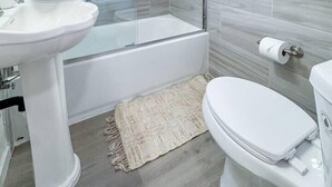 Ein modernes Badezimmer mit einer Duschkabine, einem weißen Waschbecken, einer Badewanne und einer Toilette.