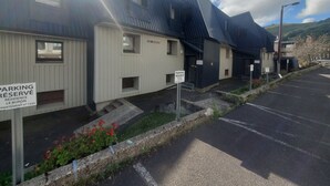 A row of modern buildings with a parking area in front.