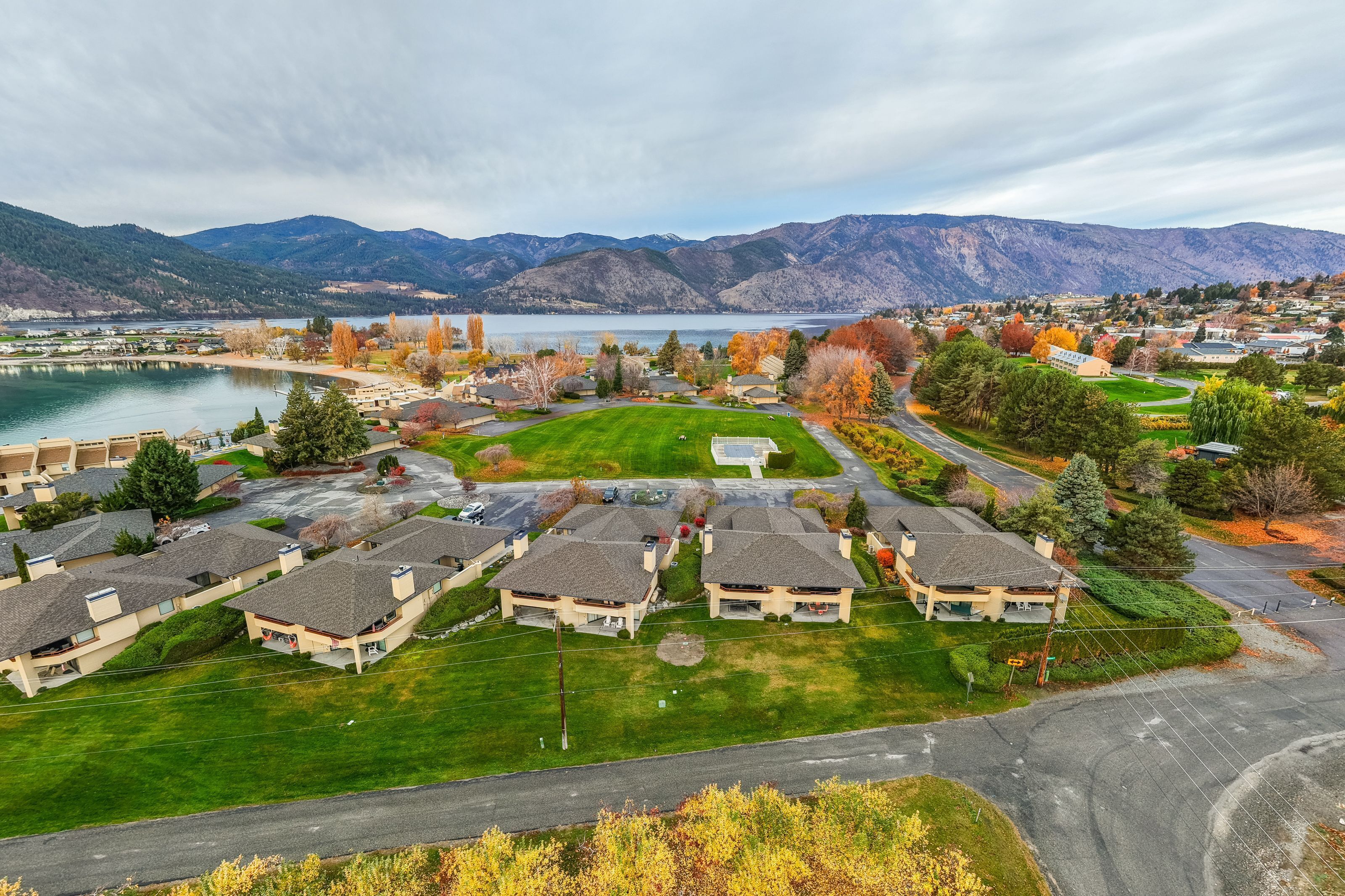 A residential area with houses, a lake, and mountains in the background.