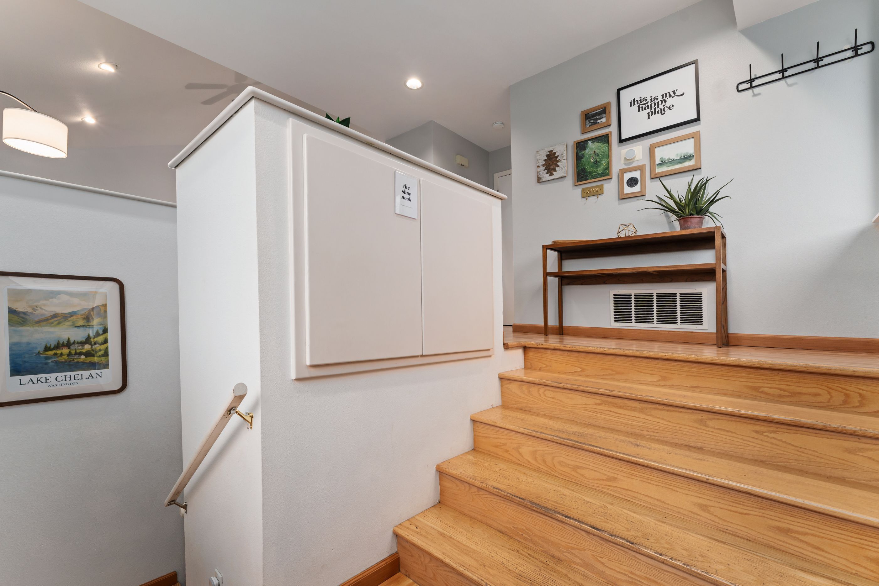 A staircase with wooden steps and a white wall with a framed picture and a sign.