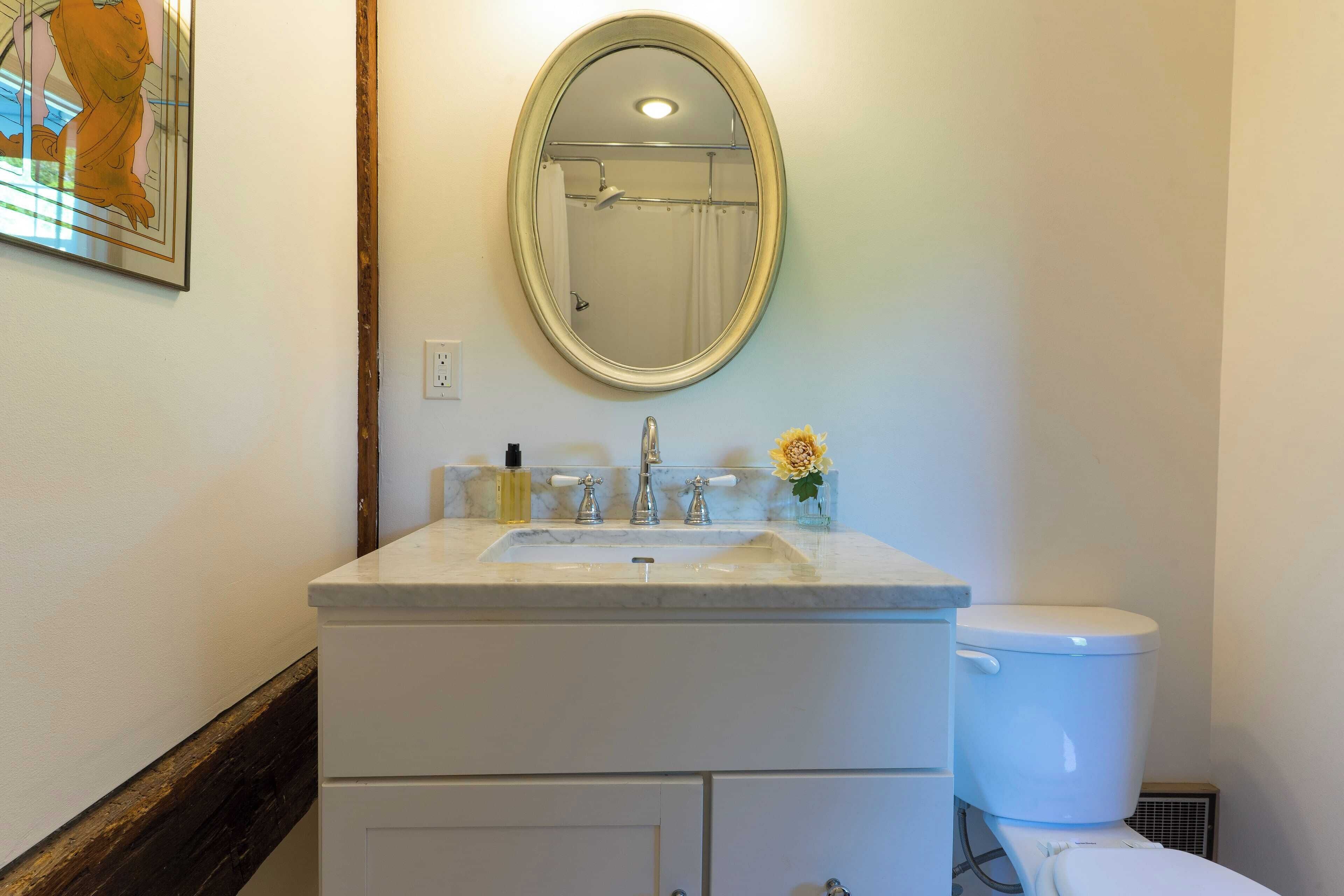 Baño con lavamanos, espejo e inodoro blancos.