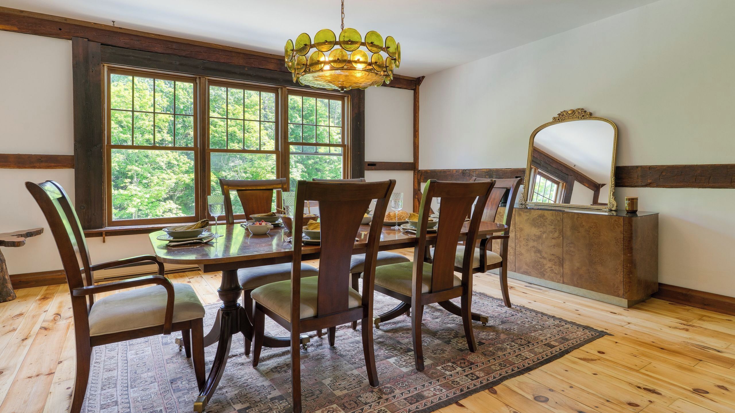 Un coin repas avec une table en bois, des chaises, un tapis et un lustre.