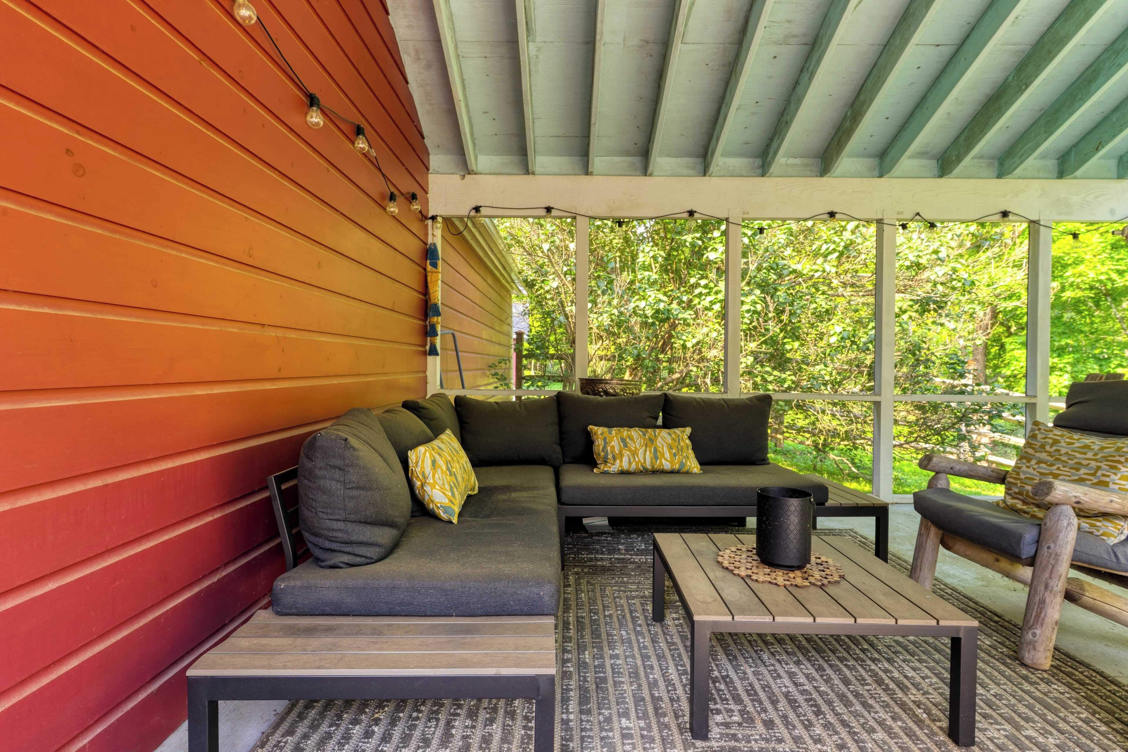 Eine überdachte Veranda mit einer hölzernen Bank, einem Sofa und einem Tisch.
