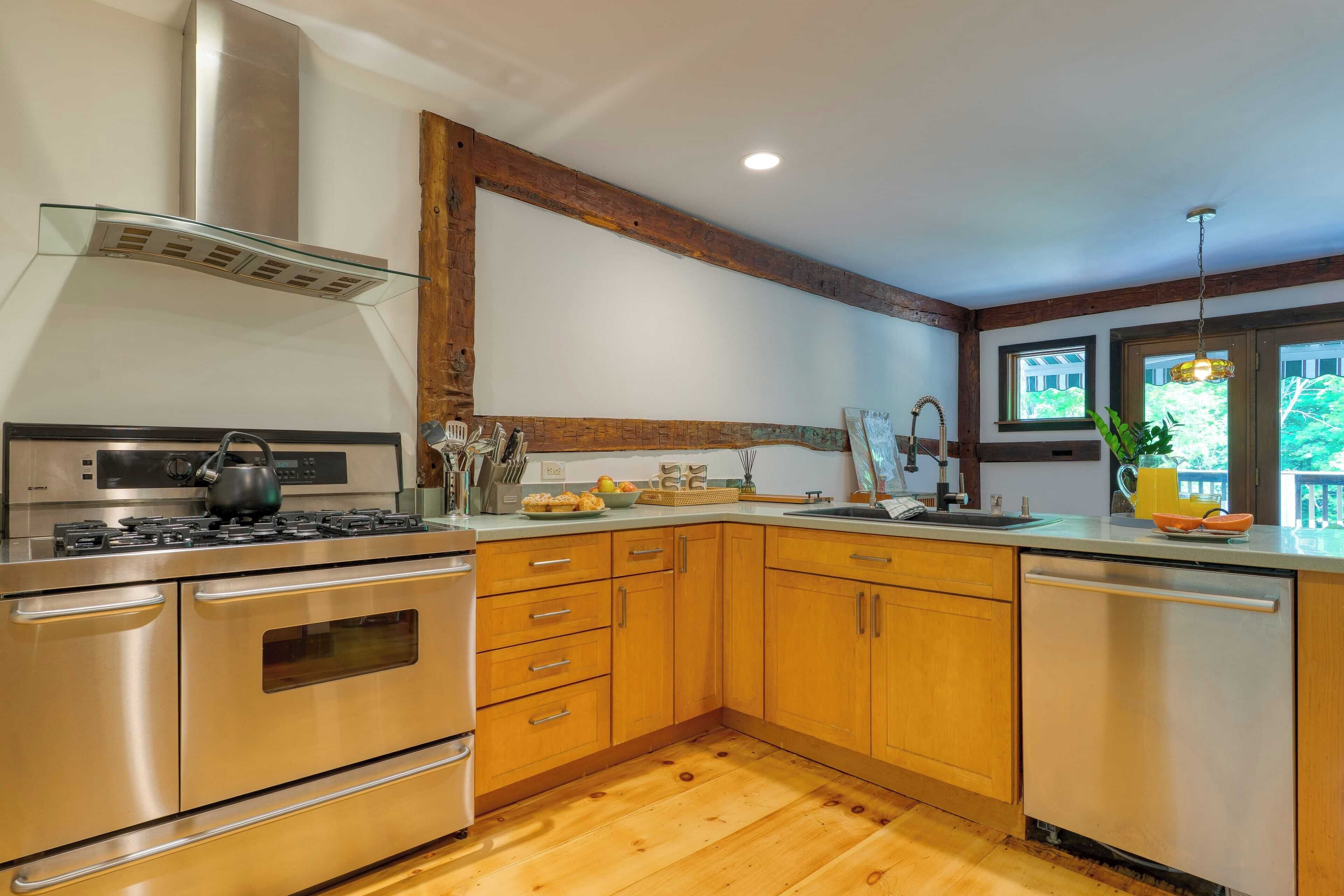 A modern kitchen with stainless steel appliances, wooden cabinets, and a glass range hood.