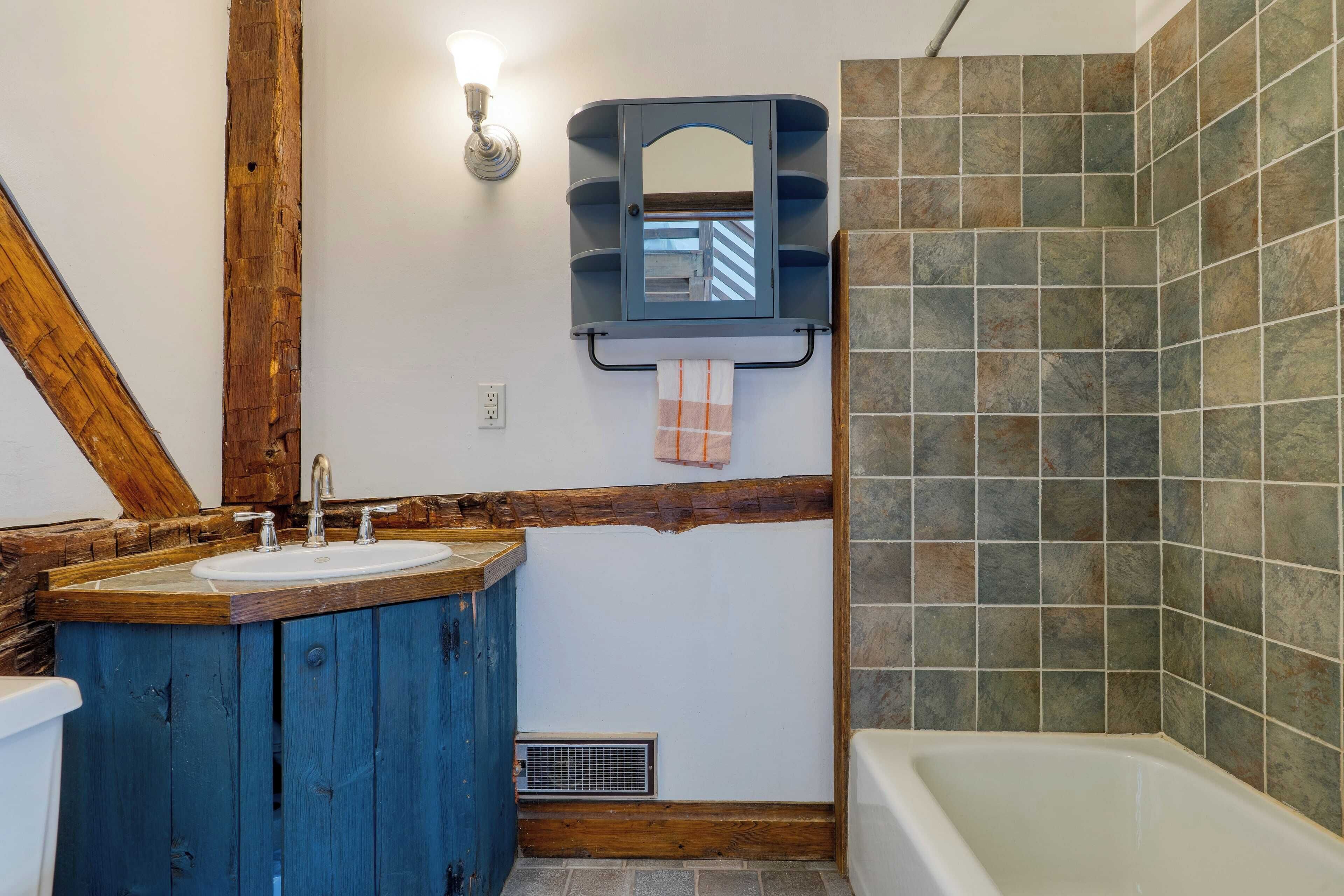 Ein Badezimmer mit einem Holzbadezimmer-Möbel, einem Waschbecken, einem Spiegel und einer Badewanne.