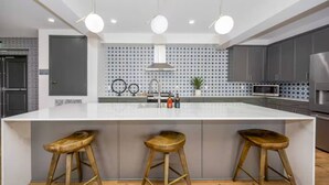 A modern kitchen with a large island, bar stools, and a patterned backsplash. - NEW LUX Modern Retreat  Views  Parking  Workspaces (San Diego)
