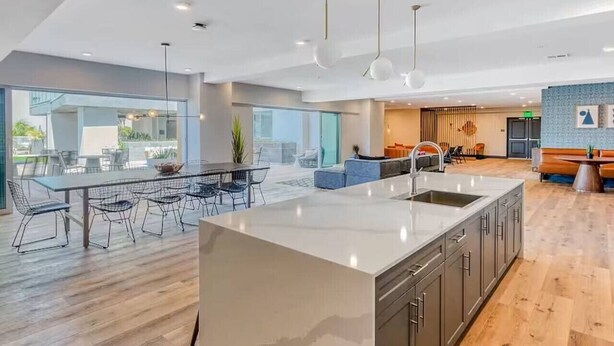 A modern kitchen with a large island, a dining area with a long table and chairs, and a seating area with a sofa and coffee table. - NEW LUX Modern Retreat  Views  Parking  Workspaces (San Diego)