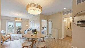 A spacious living area with a round dining table, a sofa, and a large window. - NEW LUX Modern Retreat  Views  Parking  Workspaces (San Diego)