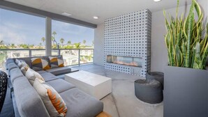 A modern outdoor living area with a sofa, coffee table, and a fireplace. - NEW LUX Modern Retreat  Views  Parking  Workspaces (San Diego)