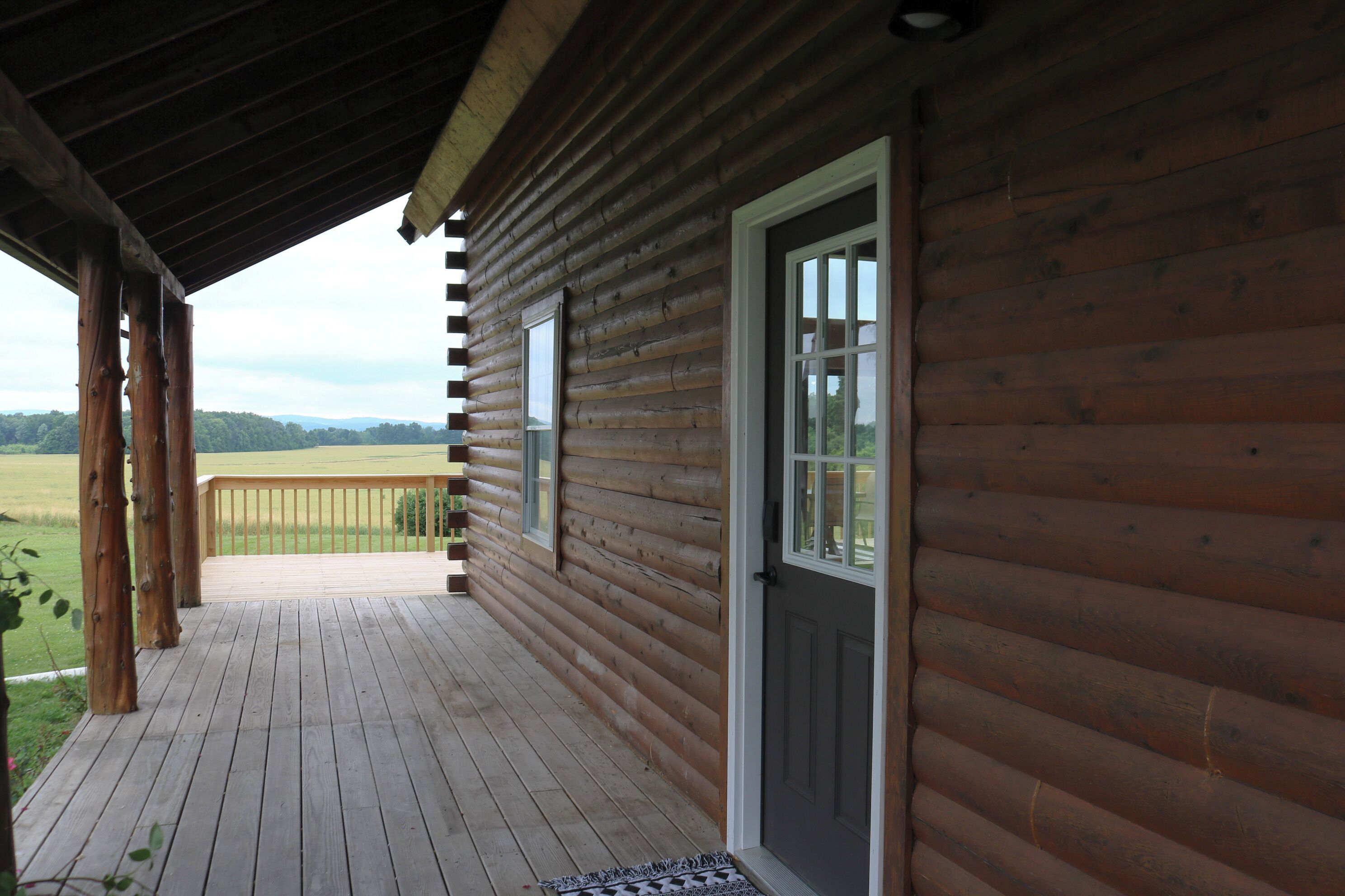 A wooden cabin with a porch, a door, and windows.