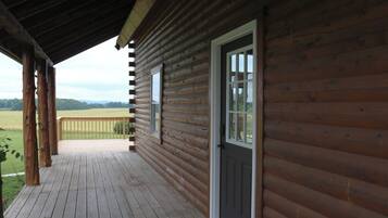 A wooden cabin with a porch, a door, and windows.