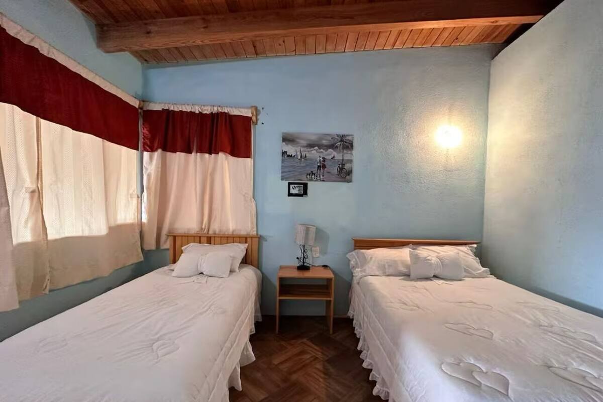 Une chambre avec deux lits simples, une table de chevet, une lampe et un tableau au mur.