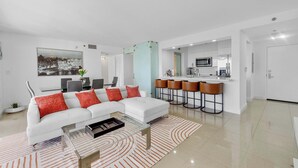 A modern living room with a white sofa, red cushions, a glass coffee table, and a patterned rug. - Luxury Brickell Penthouse Ocean Views Rooftop Pool (Miami)