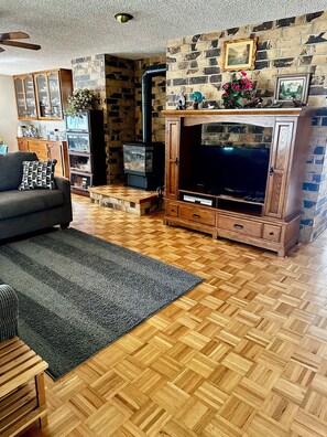 A cozy living room with a fireplace, wooden flooring, a sofa, and a TV.