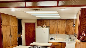 A kitchen with wooden cabinets, a white refrigerator, a gas stove, and three wooden bar stools.