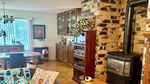 A cozy living room with a wooden herringbone floor, a sofa with dog-themed cushions, a fireplace, and a brick wall.