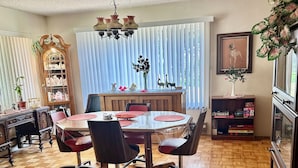 A dining area with a round table, chairs, a chandelier, and a bookshelf.