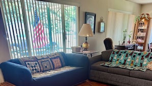 A living room with a blue sofa, a patterned rug, and a wooden herringbone floor.