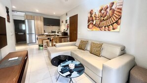 Una sala de estar moderna con un sofá, una mesa de centro y una cocina al fondo.