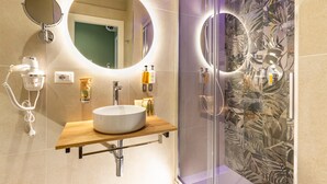 A modern bathroom with a round mirror, a wooden vanity, a white sink, and a shower with a glass door. - Elegant Double Room in the Heart of the Peaceful Colli Albani Area (ROMA)
