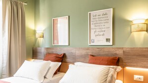A hotel room with two beds, a wooden headboard, and wall-mounted lights. - Elegant Double Room in the Heart of the Peaceful Colli Albani Area (ROMA)