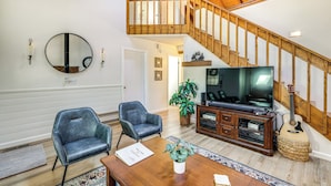 A spacious living room with a wooden staircase, a large TV, and two leather chairs. - Grill & Games: Family-Friendly Flagstaff Getaway! (Flagstaff)