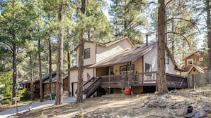 A two-story house with a deck, surrounded by tall pine trees. - Grill & Games: Family-Friendly Flagstaff Getaway! (Flagstaff)