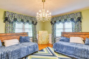 A room with two beds, a chandelier, patterned curtains, and a large abstract painting. - 78-Acre Retreat Near Campbell U: Fish, Play, Relax (Coats)